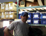 Grant Baker (Lead Technician) in front of warehouse racks